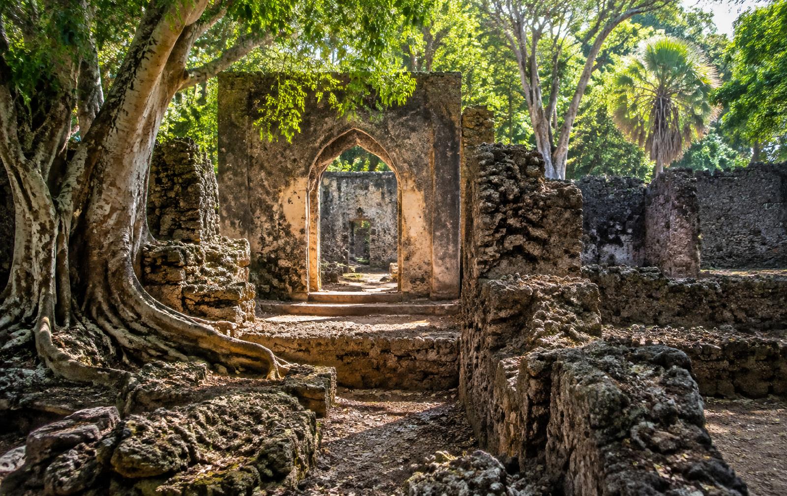 Ancient coral-stone archway among trees at Gede Ruins